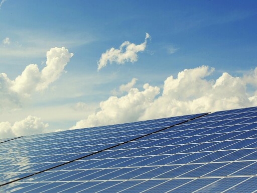 Sleek modern solar panels under a vibrant blue sky with clouds, symbolizing clean energy.