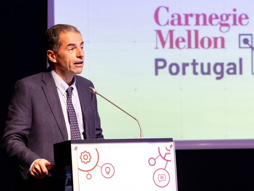 Professor Manuel Heitor a discursar em púlpito, no âmbito do programa Carnegie Mellon Portugal cujo título aparece em tela em fundo