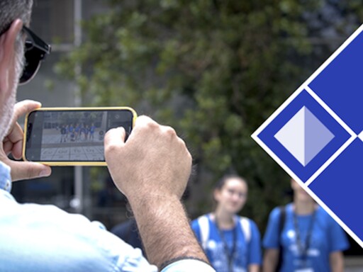 Plano aproximado da mão de um homem a tirar fotografias com telemóvel a estudantes da Faculdade de Ciências